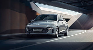 Side-front view of orange Grandi10 with lakeside view at night