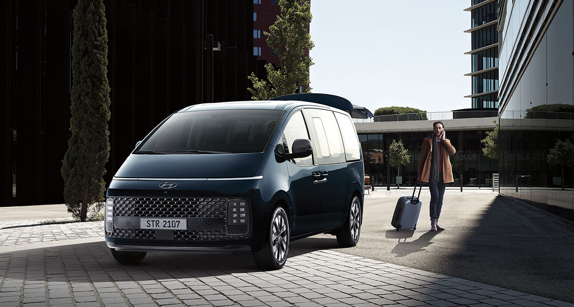 Side-front view of orange Grandi10 with lakeside view at night