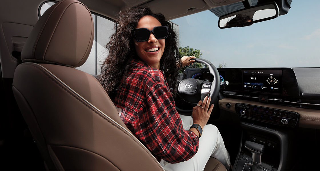 Side-front view of orange Grandi10 with lakeside view at night