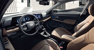 Side-front view of orange Grandi10 with lakeside view at night