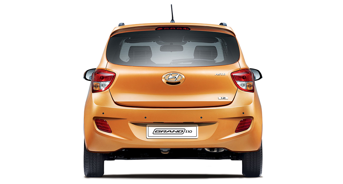 Side-front view of orange Grandi10 with lakeside view at night