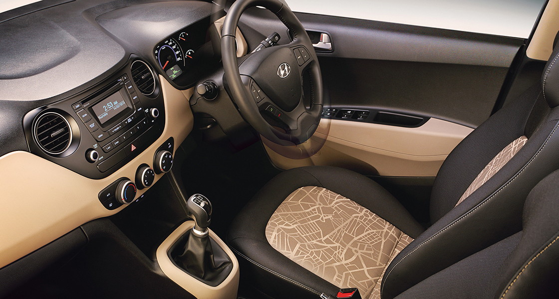 Side-front view of orange Grandi10 with lakeside view at night